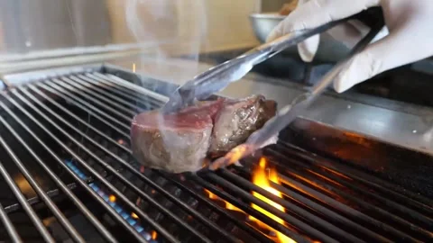 Chef Grilling Juicy Thick-Cut Beef Steak on Professional Gas Grill - Close Up Stock Footage 337677577
