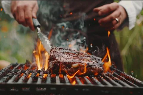 The chef is grilling steaks on the grill. Stock Photos