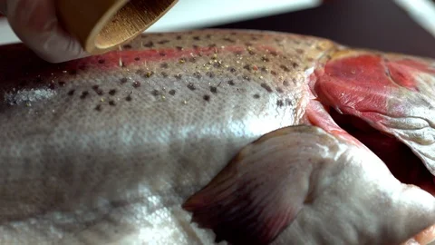 Chef grinding pepper onto a raw salmon trout Stock Footage 105132934