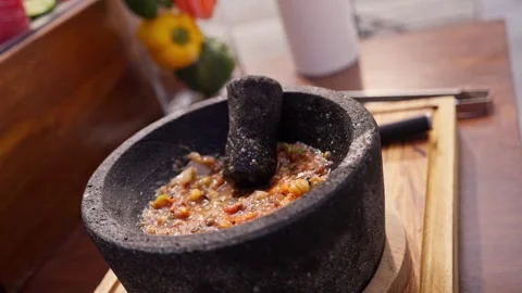 Chef grinds and prepares fresh roasted mexican salsa in a stone molcajete bowl Stock Footage 288038791