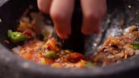 Chef grinds and prepares fresh roasted mexican salsa in a stone molcajete bowl Vidéo 288038793