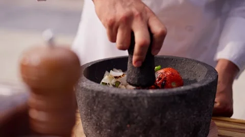 Chef grinds and prepares fresh roasted mexican salsa in a stone molcajete bowl Stock Footage 288038795