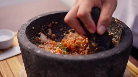 Chef grinds and prepares fresh roasted mexican salsa in a stone molcajete bowl Stock Footage 288038797