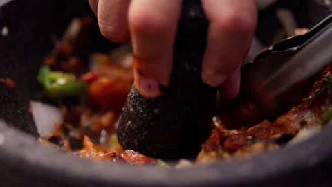 Chef grinds and prepares fresh roasted mexican salsa in a stone molcajete bowl Vidéo 288038806