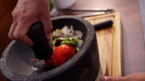 Chef grinds and prepares fresh roasted mexican salsa in a stone molcajete bowl Stock Footage 288038821