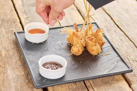 Chef hand adding sesame to fried shrimps. Stock Photos