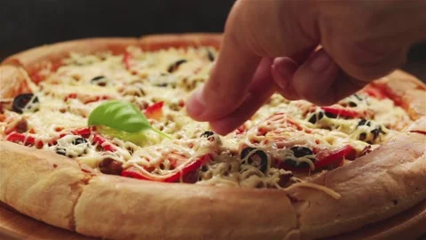 Chef hand places fresh basil leaves on baked pizza close up Stock Footage 116776619