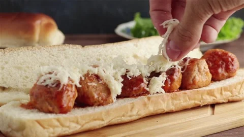 Chef hand places mozzarella cheese on meatballs sandwich close up Stock Footage 249372260