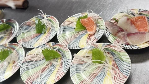 Chef hand-plating fresh Fukui salmon sashimi onto small dishes Stock Footage 339424969