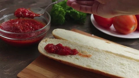 Chef hand put tomato sauce on loaf using spoon prepare sandwich Stock Footage 155893154