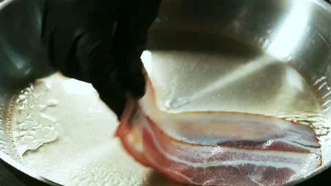 Chef hand putting the slices of bacon in the hot frying pan. Stock Footage 101750494