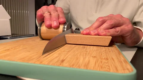 Chef hand sharpening Knife with modern grindstone on wooden board. Close up shot Video stock 146156262