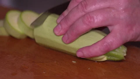 Chef Hand Slicing Fresh Green Zucchini on a Wooden Cutting Board in Kitchen Stock Footage 339646880