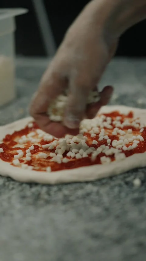 Chef hand sprinkling mozzarella cheese on pizza dough Stock Footage 327465911