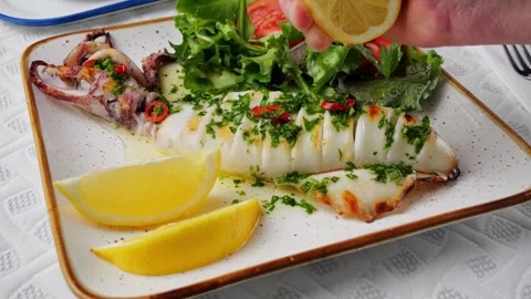 Chef hand squeeze lemon on squid grilled. Cilantro parsley sauce. Slow motion Stock Footage 263980467