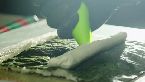Chef hand squeeze soft cream cheese onto nori with rice Stock Footage 324804351