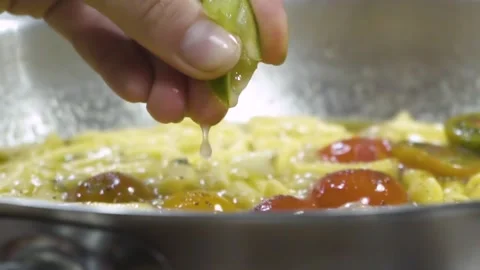 Chef hand squeezing lime juice over ravioli pasta sauce in pot Stock Footage 150590783