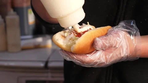 Chef Hand Squeezing Mayonnaise onto Fresh Hot Dog in Bun Stock Footage 331955521