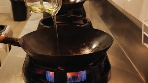 Chef handling the wok and start cooking the food in restaurant kitchen Stock Footage 152770592