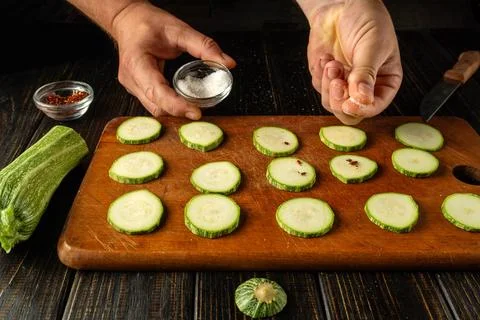 Chef hands adding salt to sliced zucchini before grilling or preparing brea.. Stock Photos