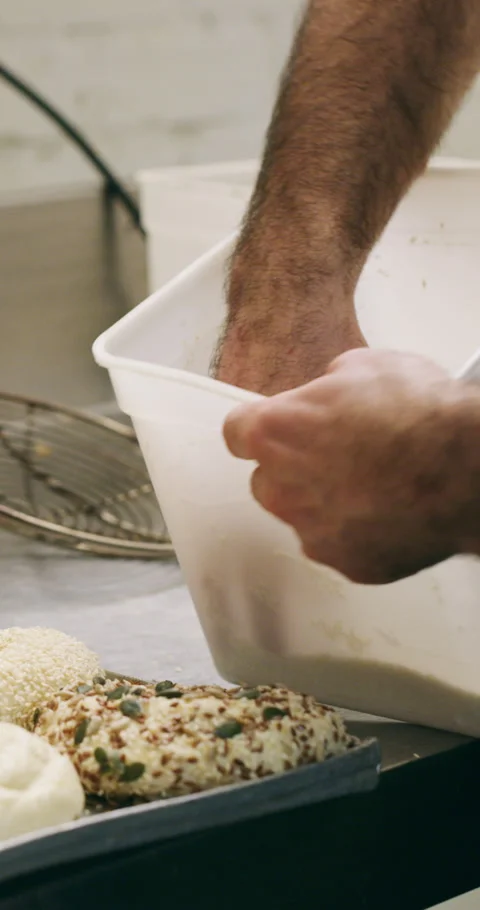 Chef, hands and bagel dough in kitchen with sesame seeds, man baking food or Stock Footage 334936504