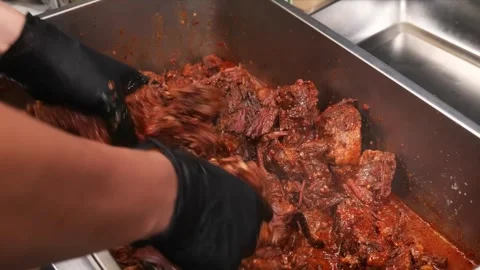 Chef Hands in Black Gloves Mixing Slow-Roasted BBQ Beef Burnt Ends in Metal Tray Stock Footage 331635629