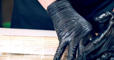 Chef hands in black gloves preparing delicious sushi rolls with avocado Stock Footage 148239084
