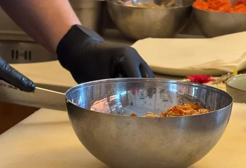 Chef hands in black gloves preparing food in a bowl, kitchen concept Stock Photos