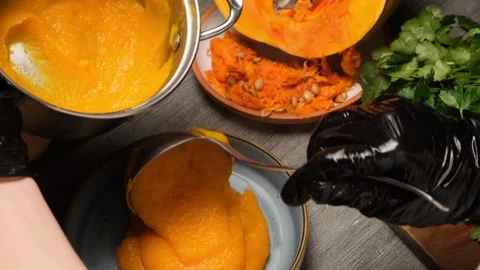 Chef hands in black gloves using ladle to serve hot vegetarian pumpkin porridge  Stock Footage 332874975