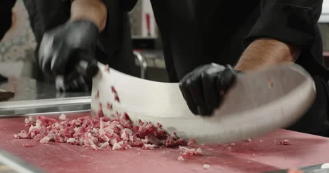 Chef hands chop the meat with a big knife. Preparation of minced meat for Stock Footage 258550540