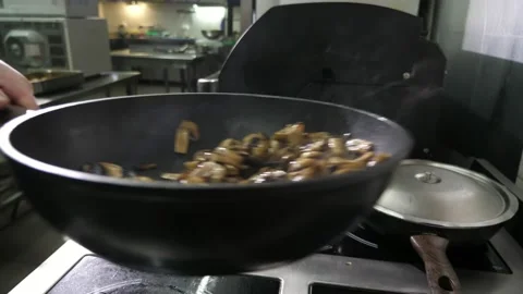 Chef hands cooking and throwing up mushrooms in a pan in kitchen in slow motion Stock Footage 135219057