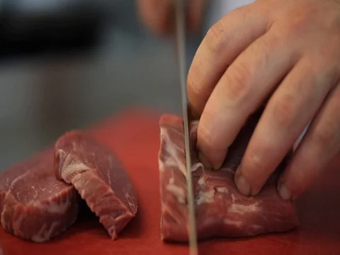 Chef hands cut raw meat on steaks on a cutting board. Close-up Stock Footage 83587450