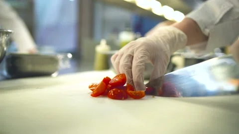 Chef hands cutting cherry tomatoes with sharp knife in kitchen, with gloves Stock Footage 131452891