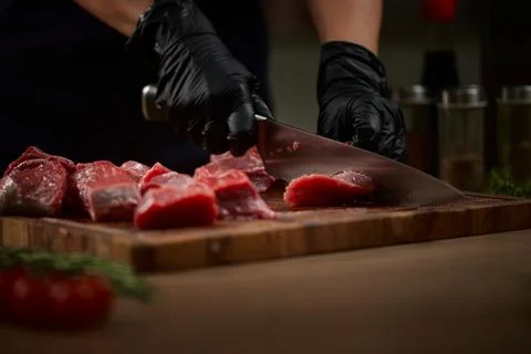 Chef hands cutting fresh raw beef on wooden board Stock Photos