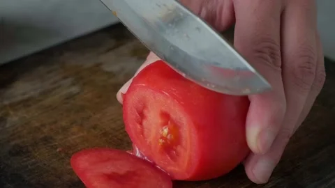 Chef hands cutting a fresh tomato with knife on wooden board Stock Footage 226141014