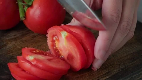 Chef hands cutting a fresh tomato with knife on wooden board. Cooking vegetarian Stock Footage 251015122