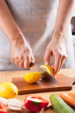Chef hands cutting lemon in kitchen Stock Photos