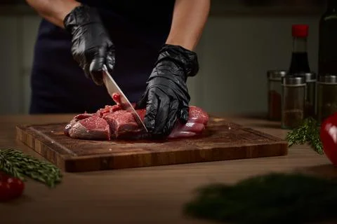 Chef hands cutting raw beef meat on cutting board Stock Photos