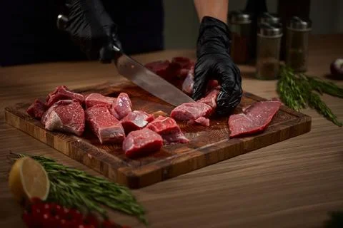 Chef hands cutting raw beef on wooden board 写真素材