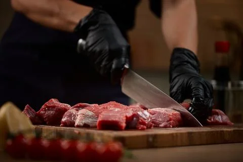 Chef hands cutting raw beef on wooden board 写真素材