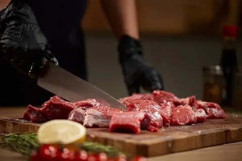 Chef hands cutting raw beef into cubes 写真素材