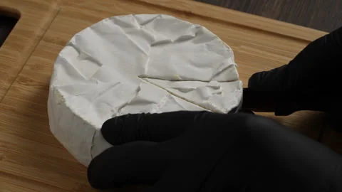 Chef hands cutting of white soft moldy Camembert cheese  on a wooden cutting Stock Footage 305894327