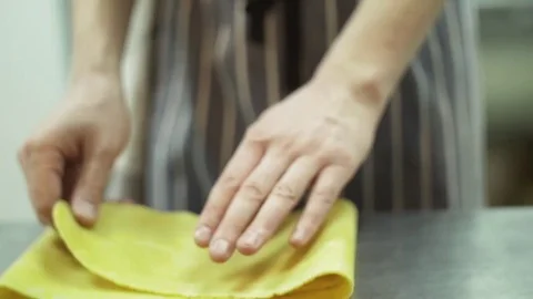Chef hands fold and turn a thin layer of dough for pasta, preparing dough to Stock Footage 74718226