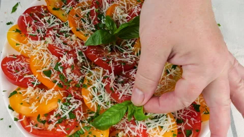 Chef hands gently place fresh basil leaves onto colorful sliced tomatoes. Stock Footage 341548002
