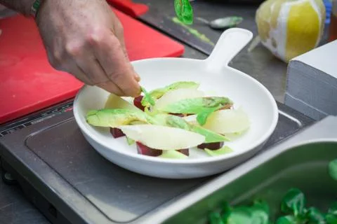 Chef hands gently spread out a salad of green apple Stock Photos