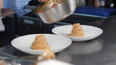 Chef hands in gloves and white uniforms serve pasta or spaghetti in tomato sauce Stock Footage 88674632
