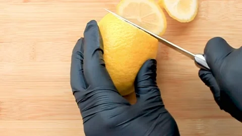 Chef hands in gloves cutting lemon on chopping board Video stock 130714775