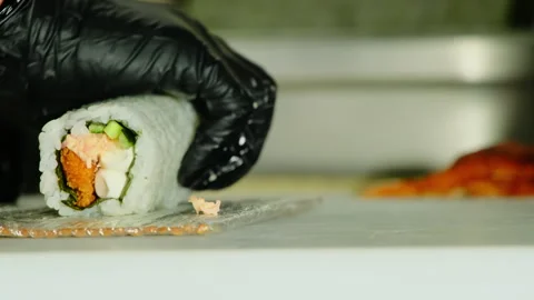 Chef hands in gloves shape sushi roll with bamboo mat on table 스톡 동영상 324804862