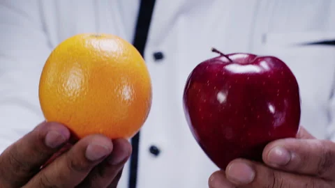 Chef Hands Hold up Apple And Orange to the camera Stock Footage 248780787