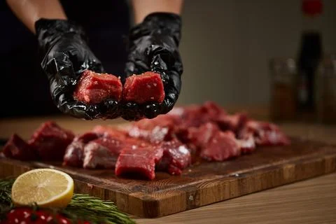 Chef hands holding raw beef cubes marinating Stock Photos
